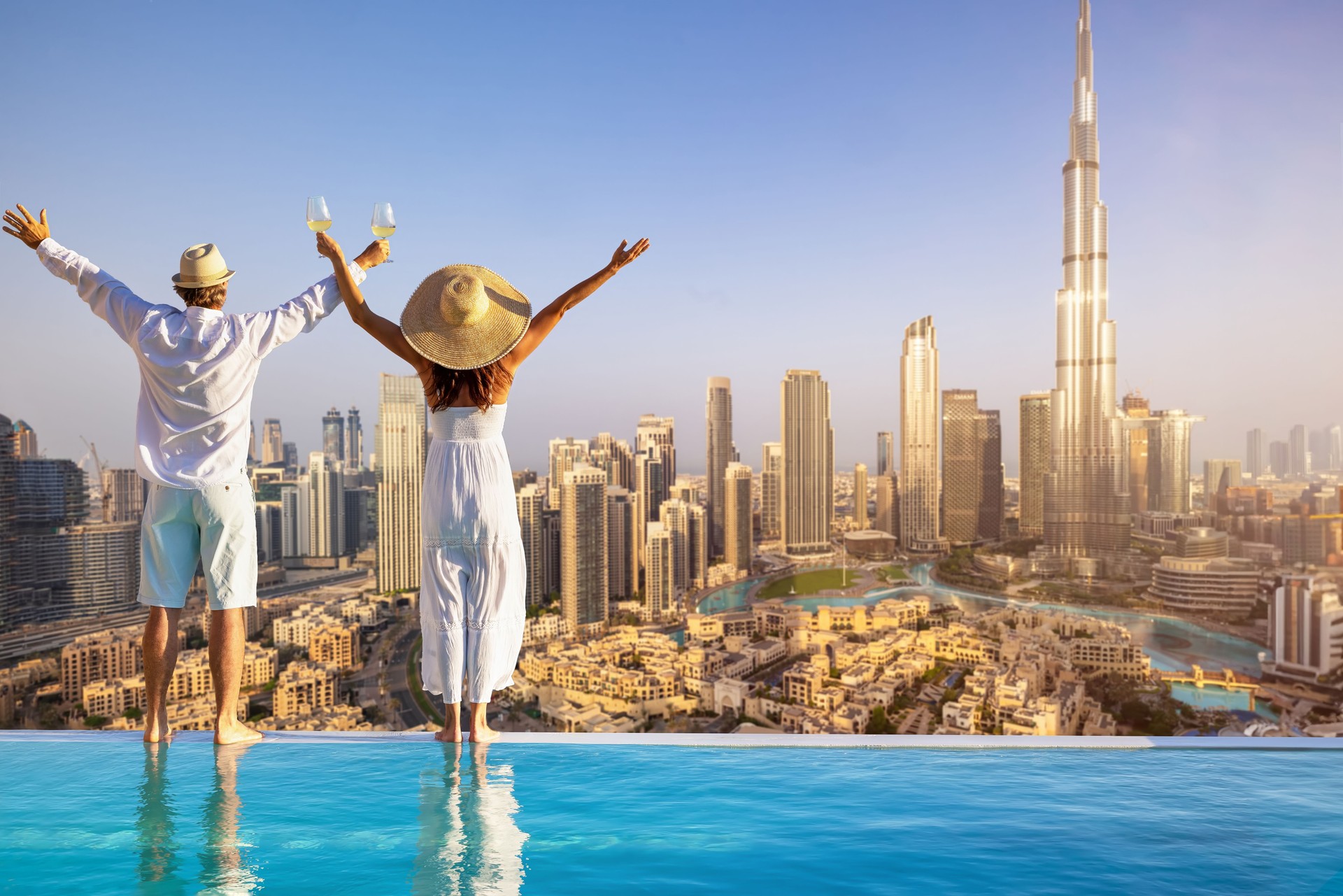 A couple stands by the pool edge and enjoys the view of the Dubai